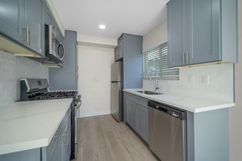 A kitchen with blue cabinets and white counter tops and a stainless steel refrigerator